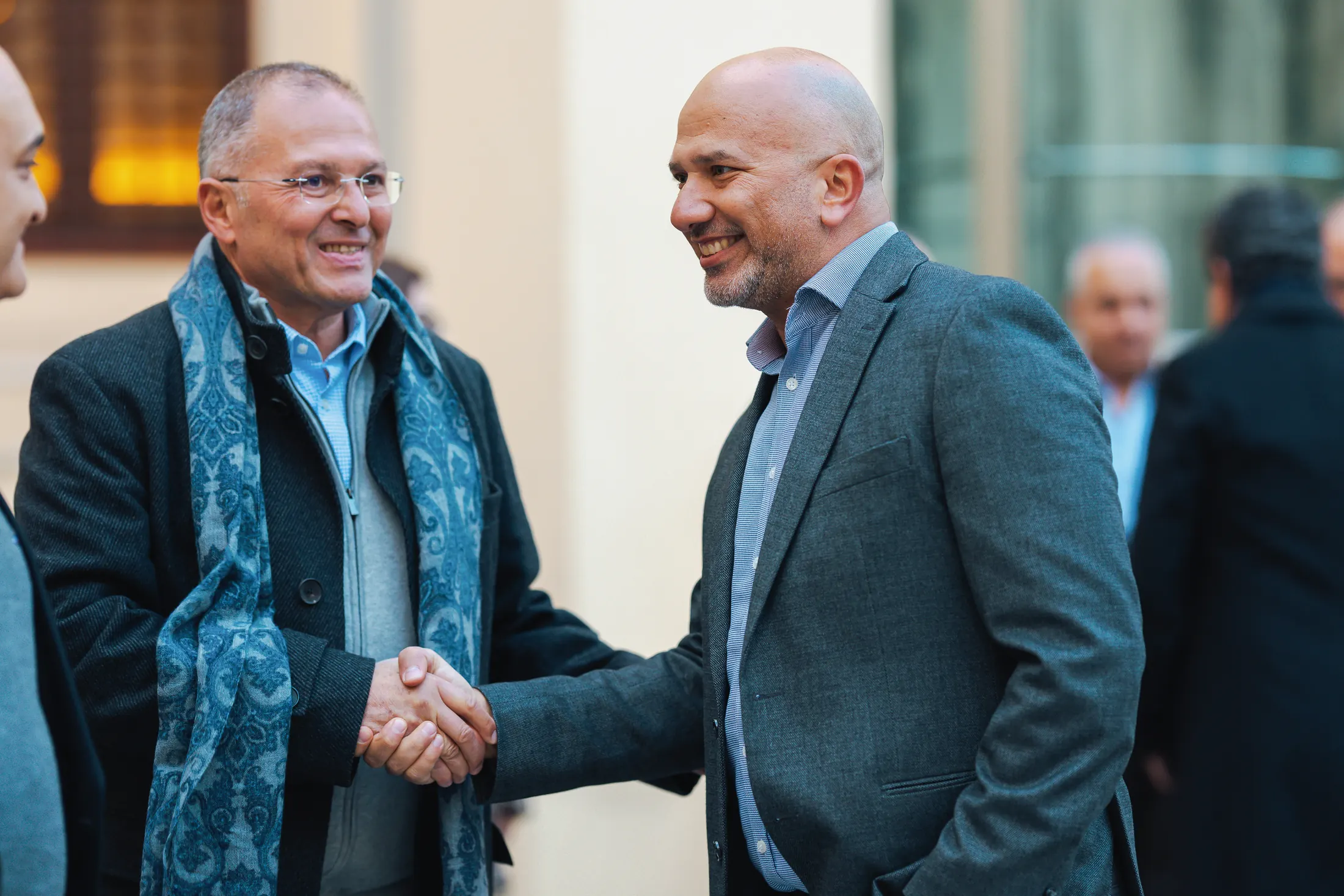 Two PGAE alumni shaking hands and reconnecting.